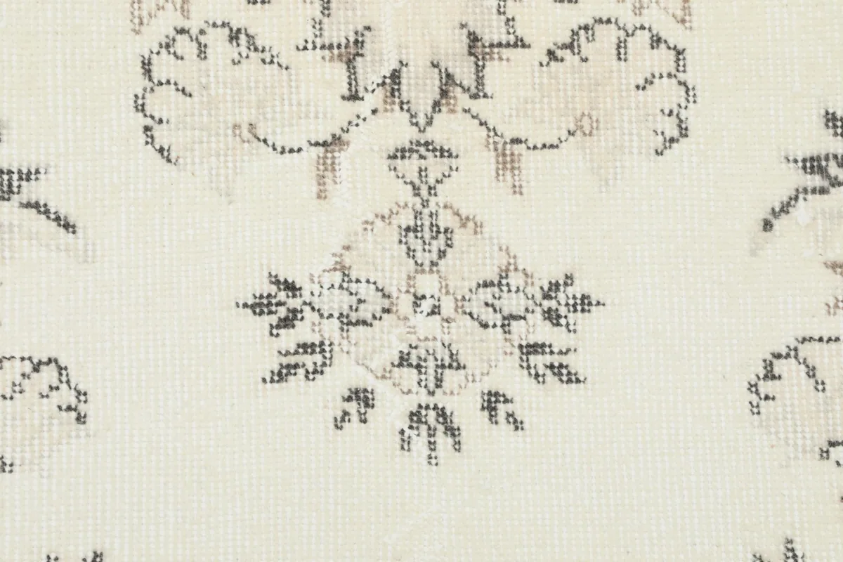 Detailed view of a floral element within the rug, showcasing the hand-knotted wool pile and gentle wear.