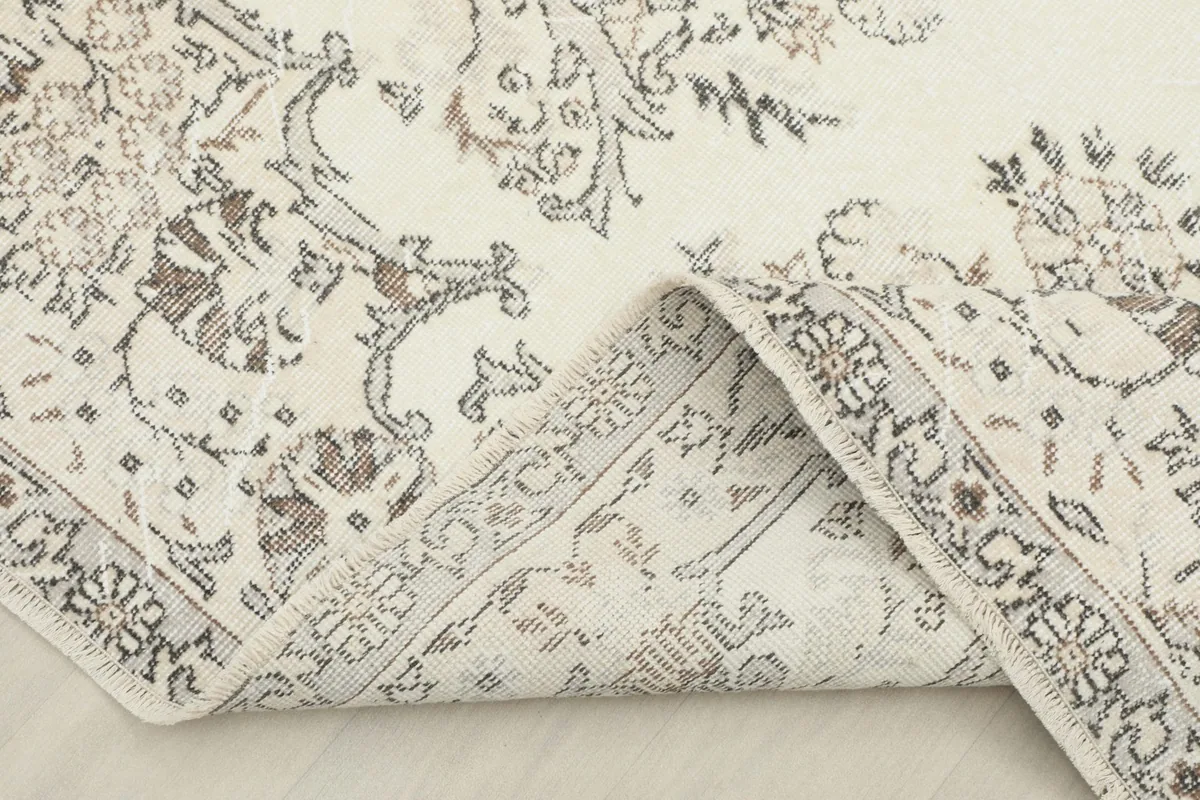 View of the vintage rug with a corner folded back, showing the cotton foundation and the reverse side.