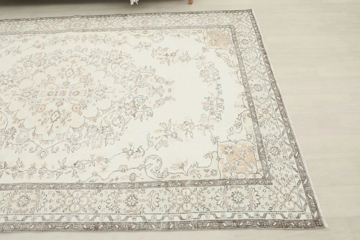 Corner view of the ivory rug, highlighting the gray border and corner motifs