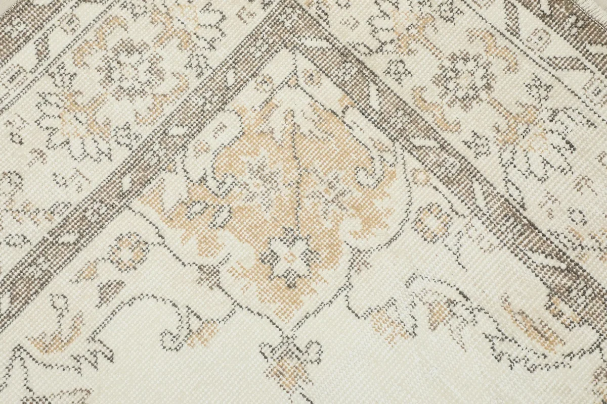 Detailed view of a corner motif with tan and gray elements on the rug