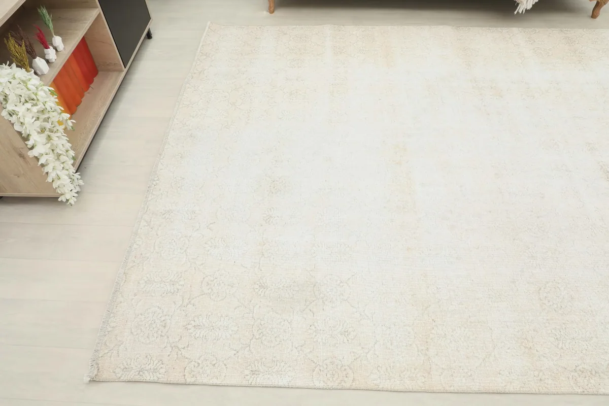 Angle view highlighting the distressed texture and faded beige patterns of the rug