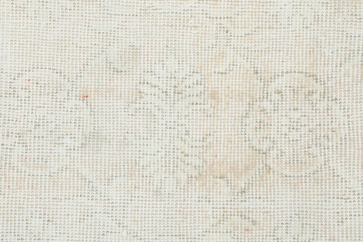 Close-up of the hand-knotted wool pile and faded floral design on the cream rug