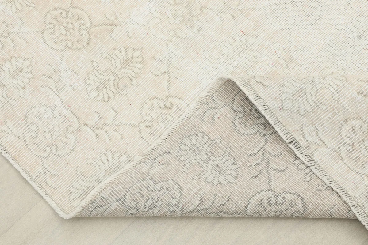 Corner of the rug folded back, revealing the reverse side with visible knotting and pattern