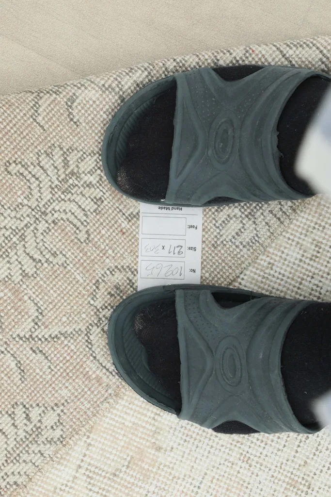 Feet in sandals next to a label on the rug, showing details and texture