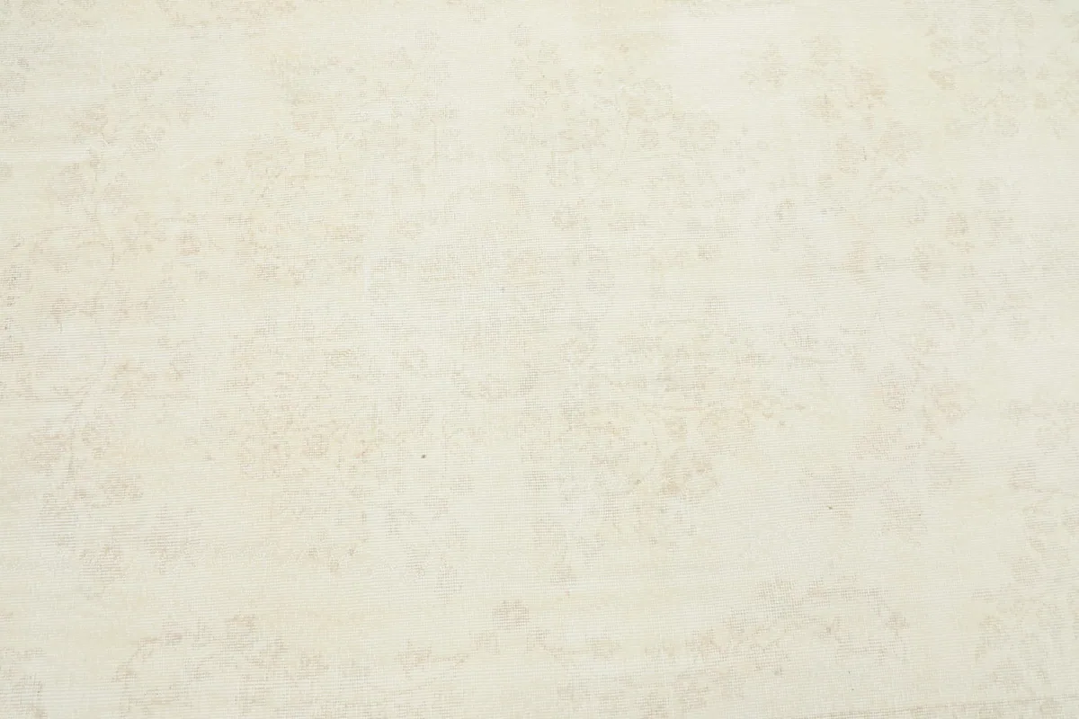 Detailed view of the rug's low pile and visible faded floral motifs