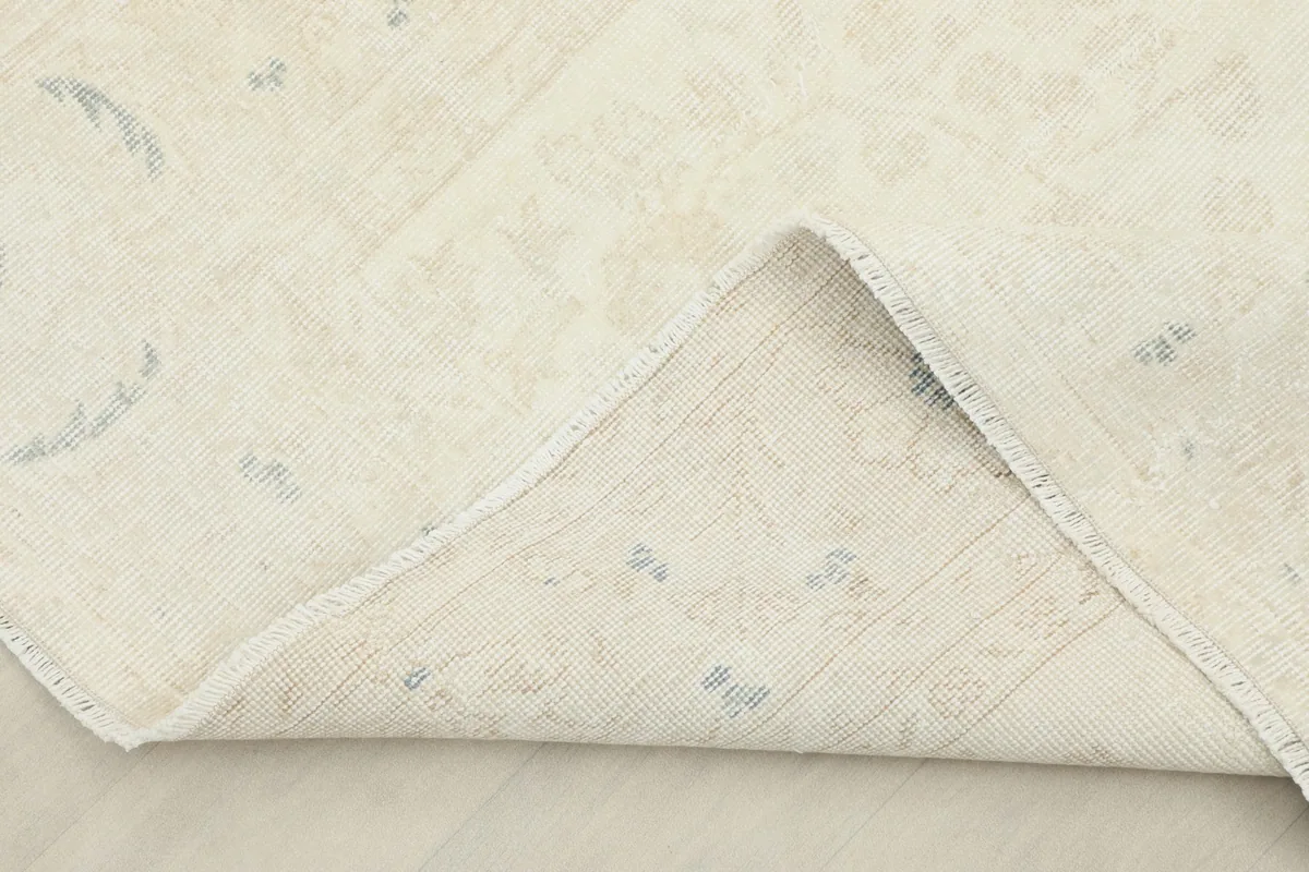 Corner of the rug folded back to show the cotton foundation and knotting