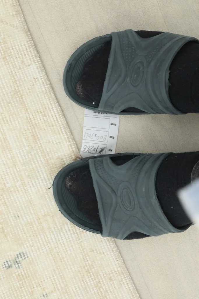 Feet on the back of the rug, showing the textile tag and scale