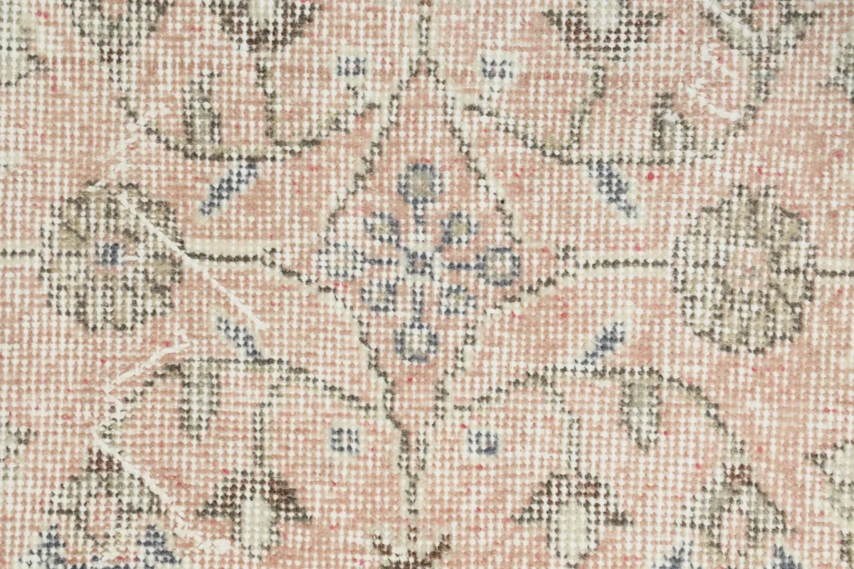 Extreme close-up of the hand-knotted wool pile, revealing the texture and faded colors of the central motif.
