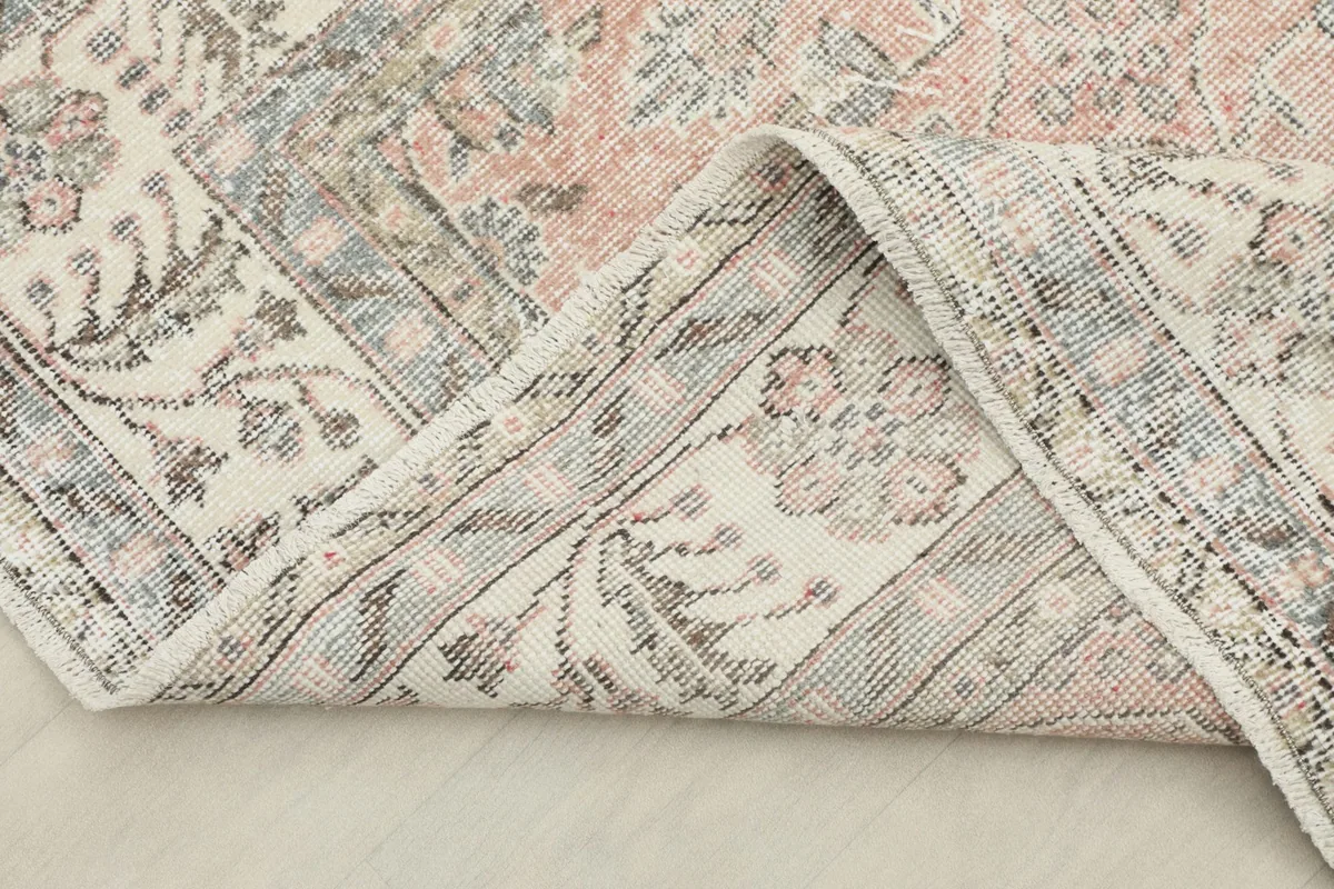 The rug folded back to show the reverse side of the border and the cotton foundation.