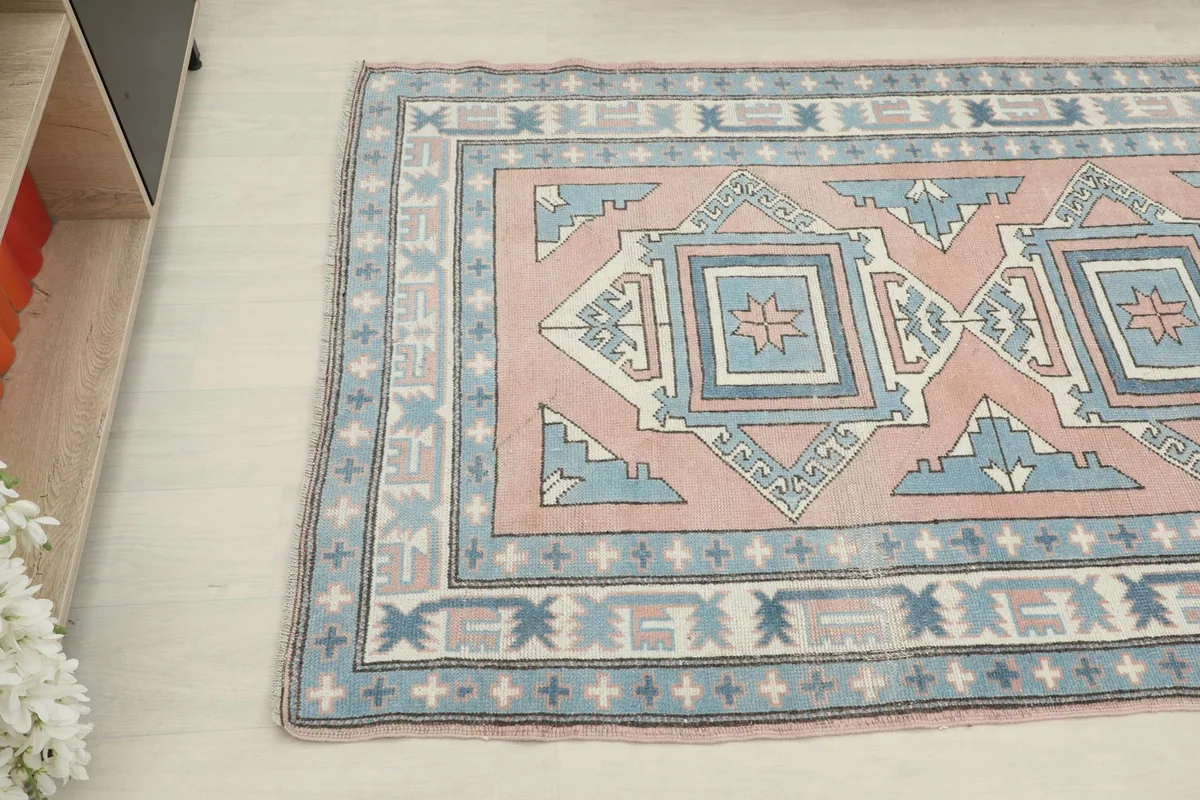Overhead angle of the vintage wool rug, highlighting the rose field and blue border details.