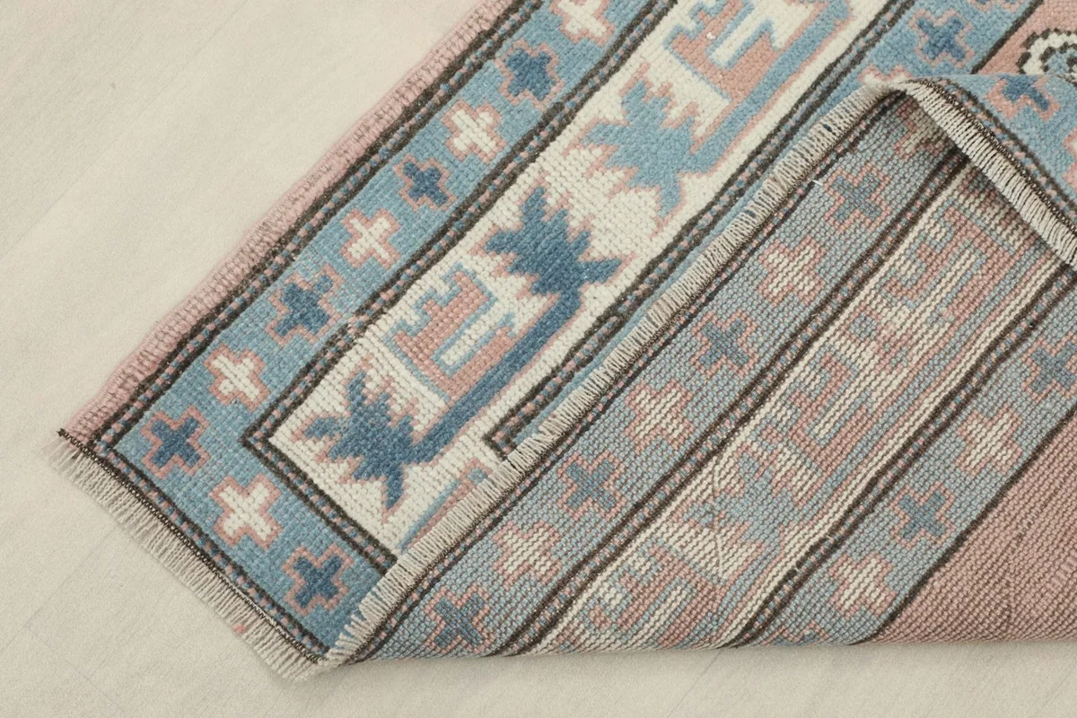Corner of the rug folded back, showing the back of the hand-knotted wool pile.