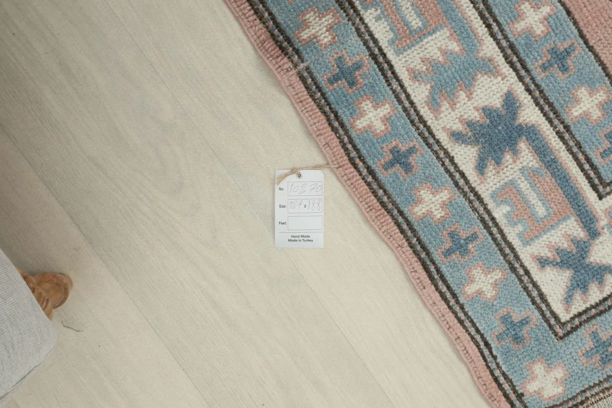 Overhead view of a small tag on the floor next to the rug, indicating product details.