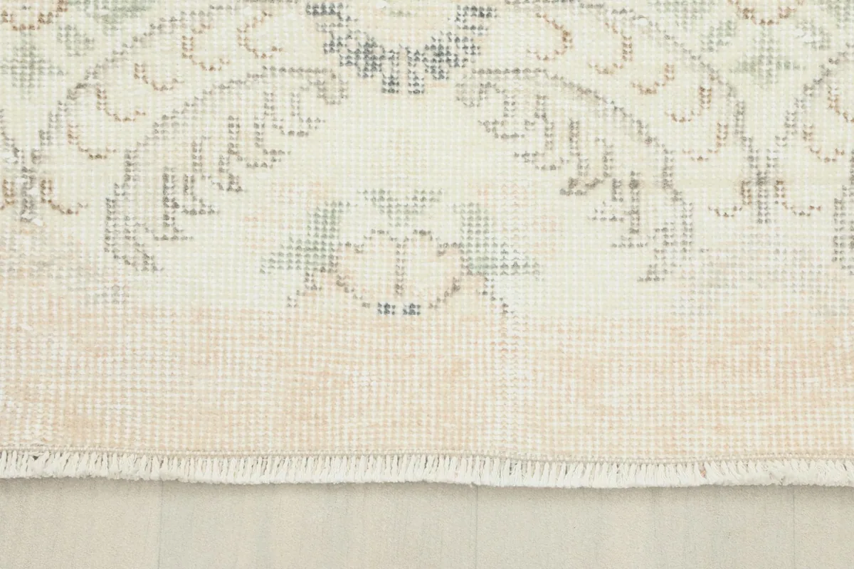 View of the rug's edge and fringe, showing the cotton foundation and the low pile.