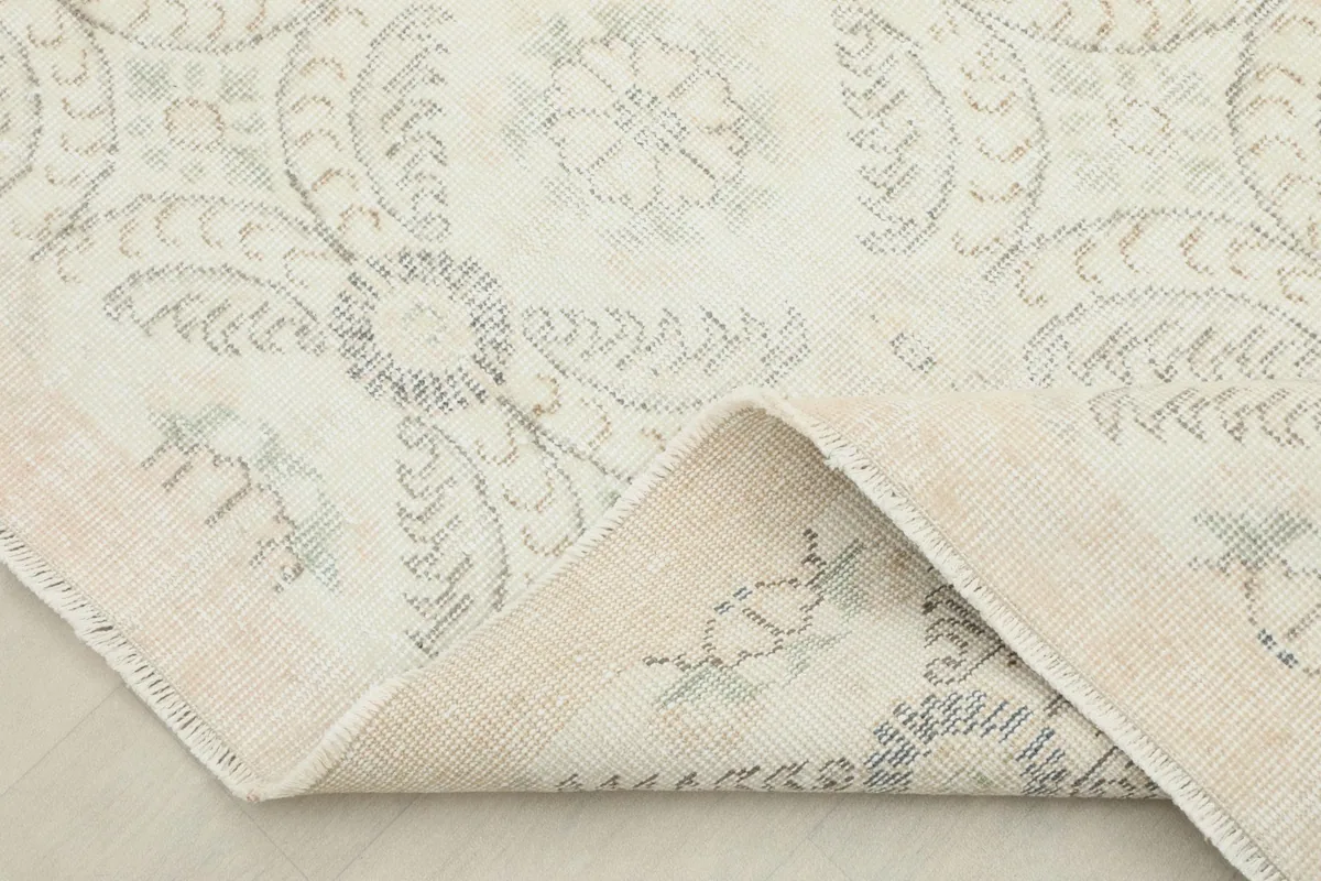 Corner of the rug folded back, showing the backside of the hand-knotted wool pile and cotton foundation.