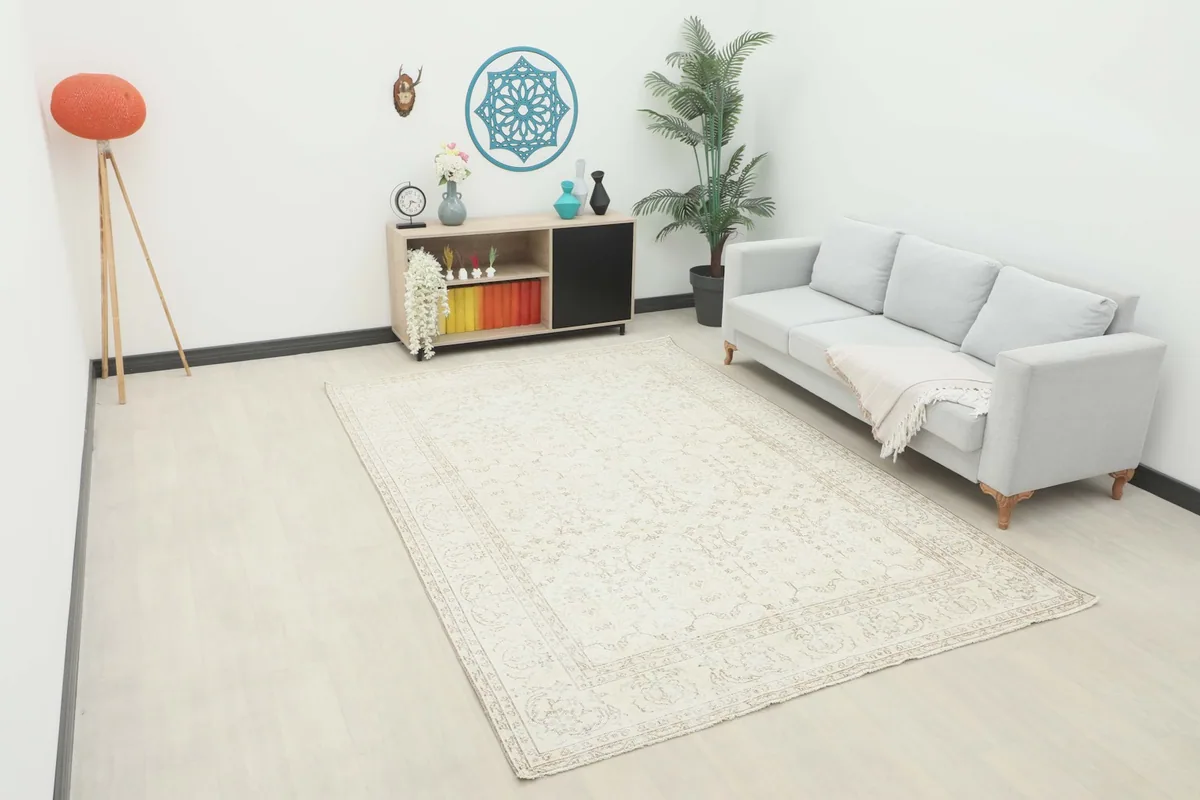 Large ivory vintage Anatolian rug displayed in a bright living room setting with a light gray sofa