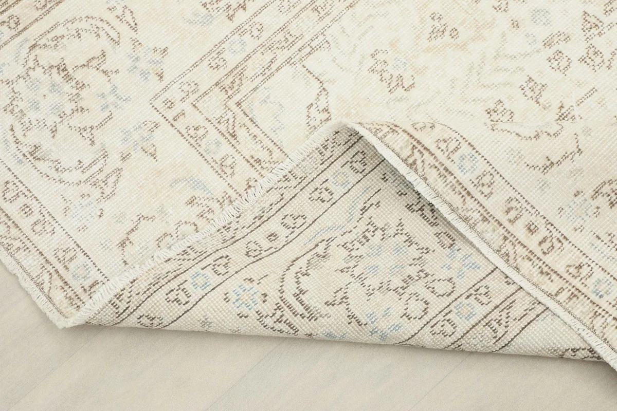 View of the rug's pile and cotton foundation as a corner is folded back, showing its construction