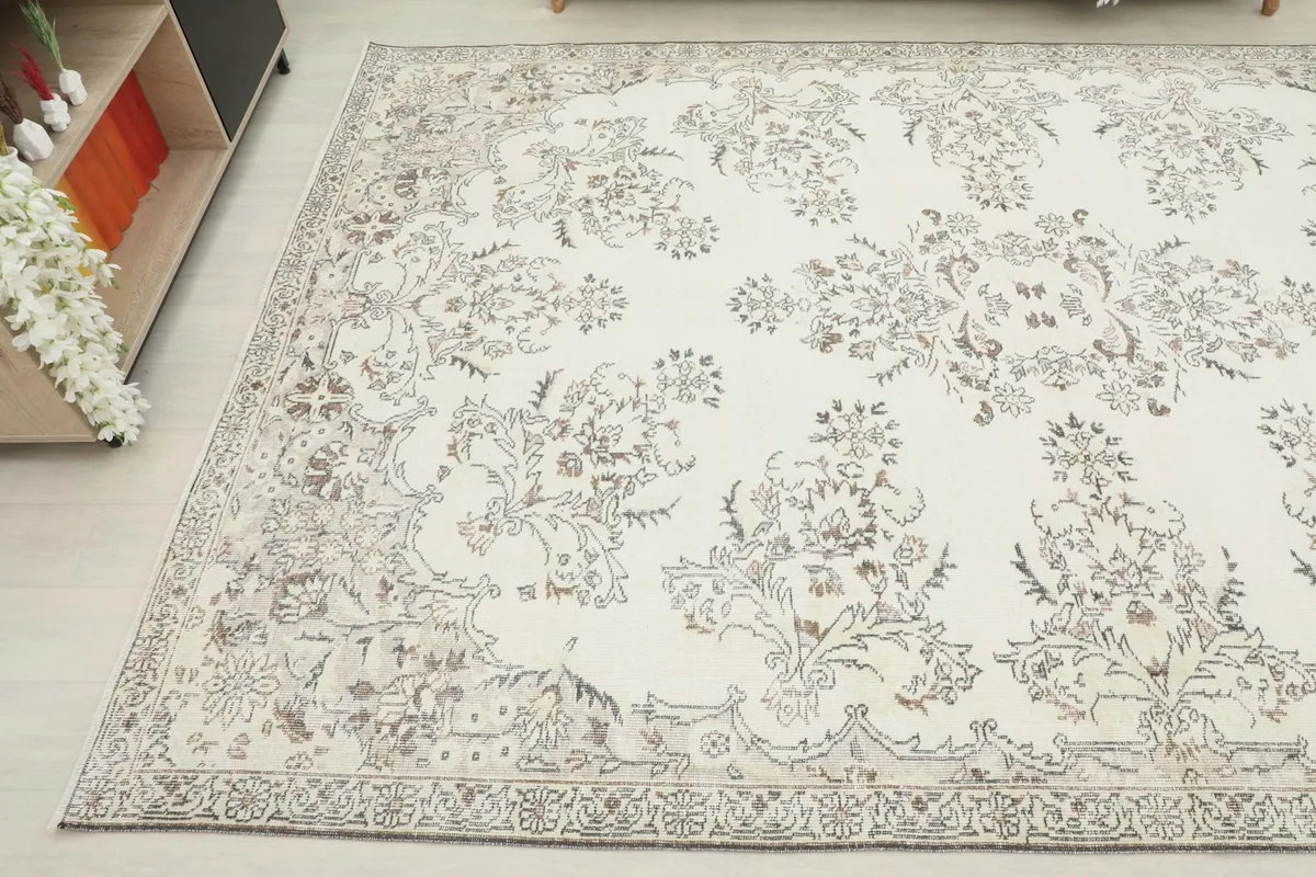 Side view of the ivory rug in a room, showing its full length and decorative motifs