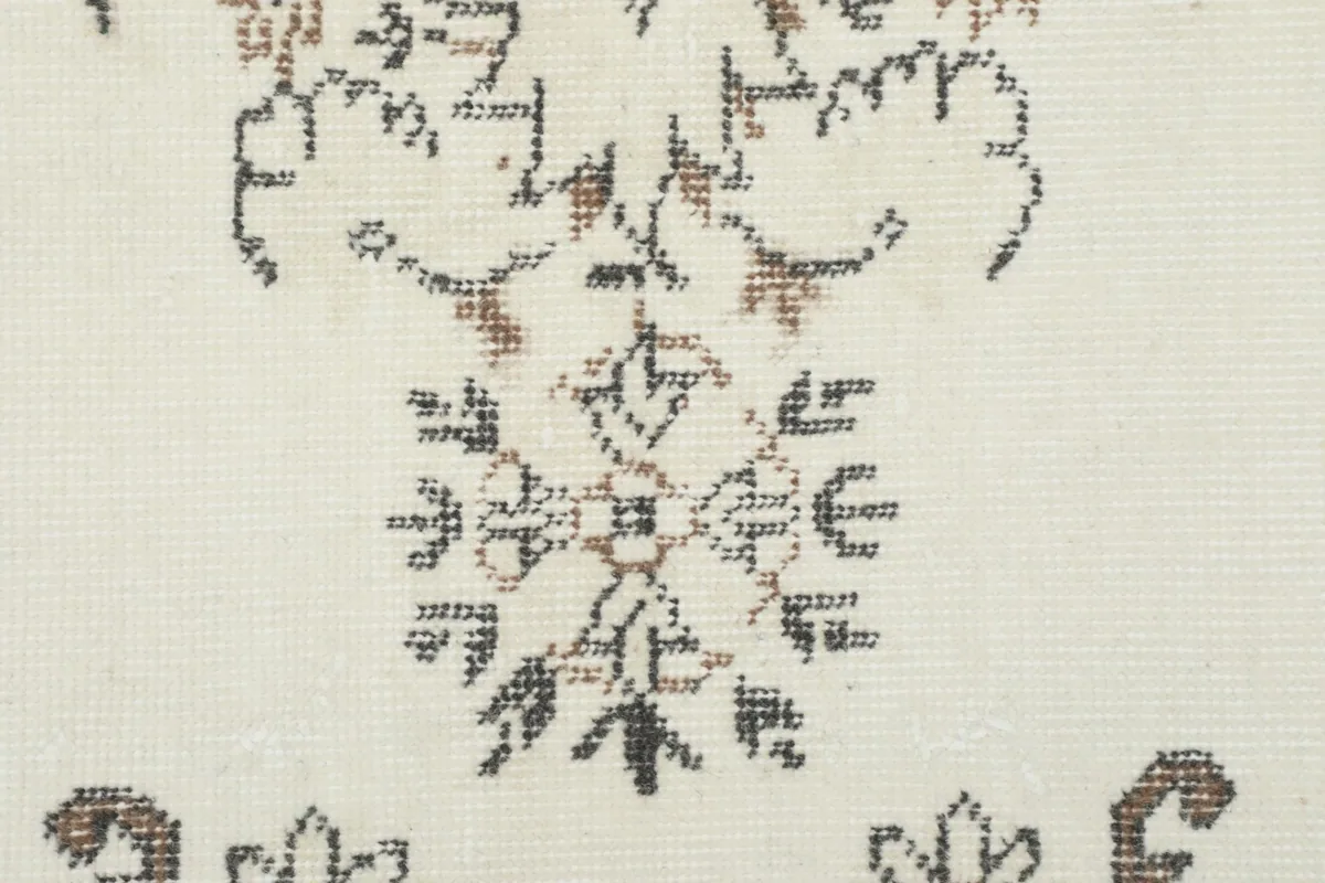 Detailed view of the hand-knotted wool pile, showing the texture and faded brown tones in the pattern