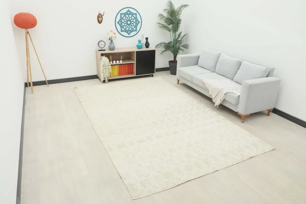 Ivory floral geometric rug displayed in a bright room with a light gray sofa and modern decor.