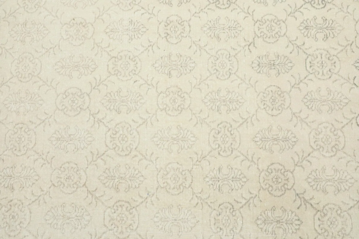 Detailed overhead shot of the ivory and gray floral geometric pattern across the rug's surface.