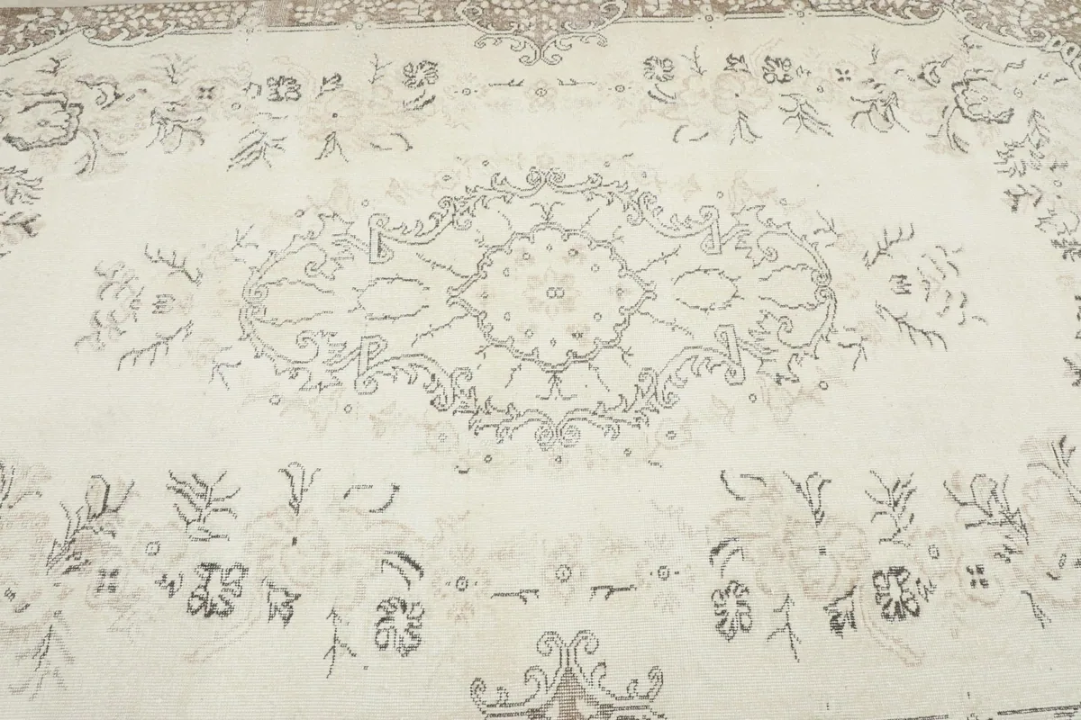 Close-up of the central medallion motif and surrounding floral patterns on the cream rug field