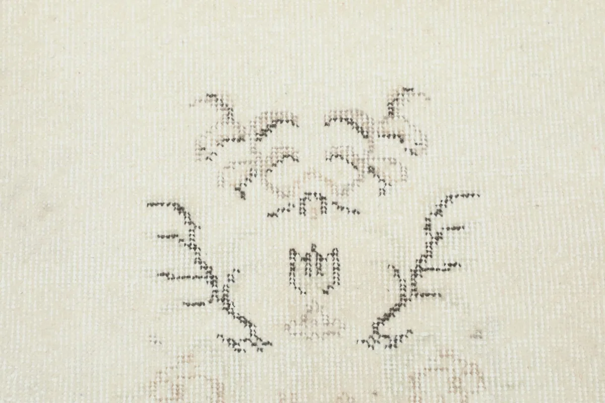 Detailed view of the specific floral and vine motifs within the cream field of the vintage rug