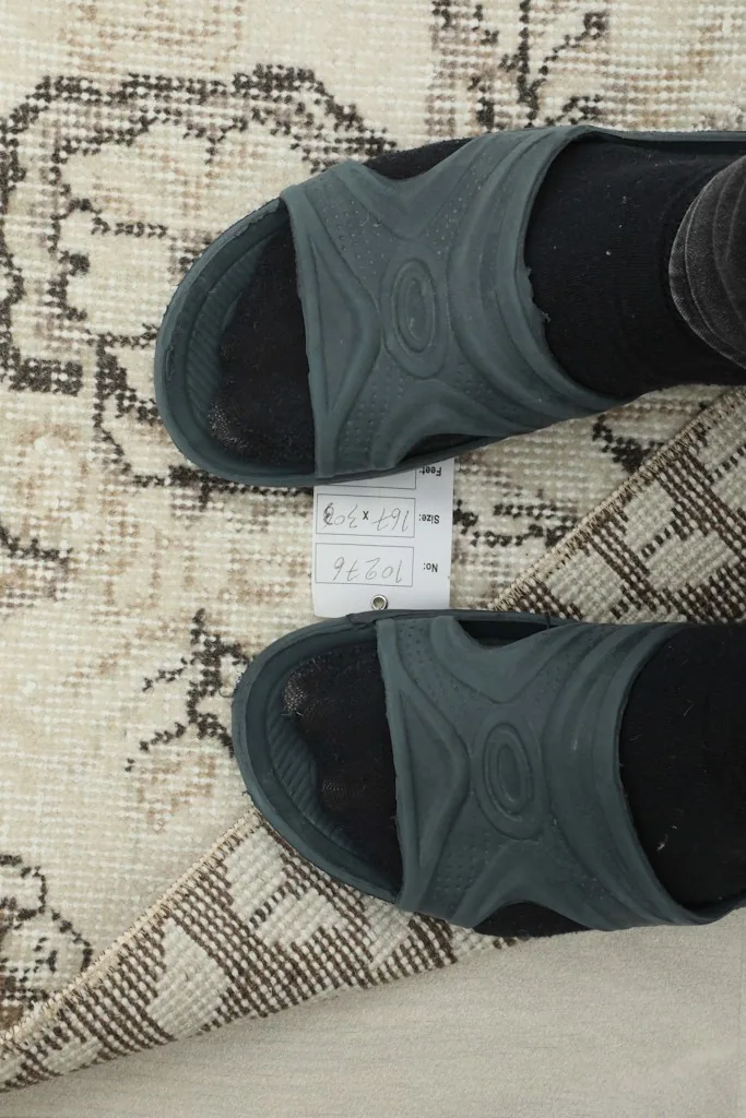 View of the rug's pile and label with feet for scale, showing the low pile height