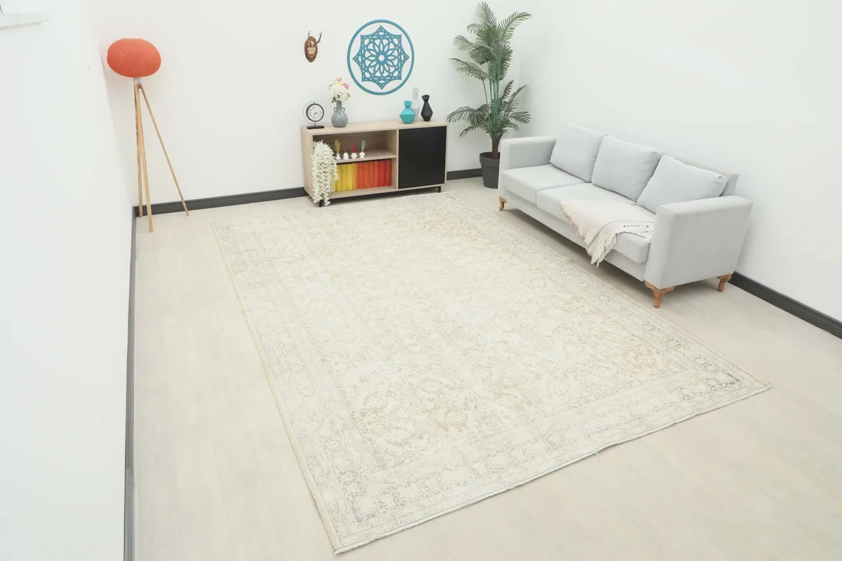 Ivory and beige vintage Anatolian rug displayed in a room setting with a light gray sofa.