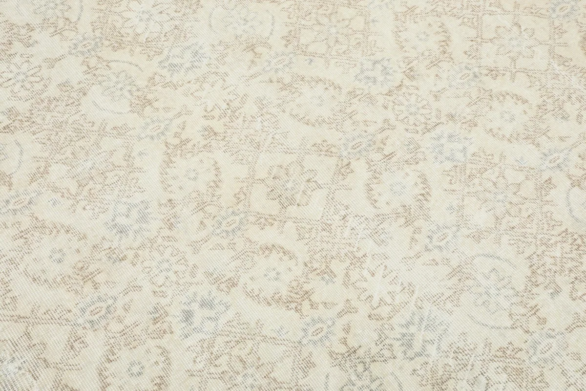 Detailed view of the rug's central field, revealing the intricate, faded floral and vine motifs.