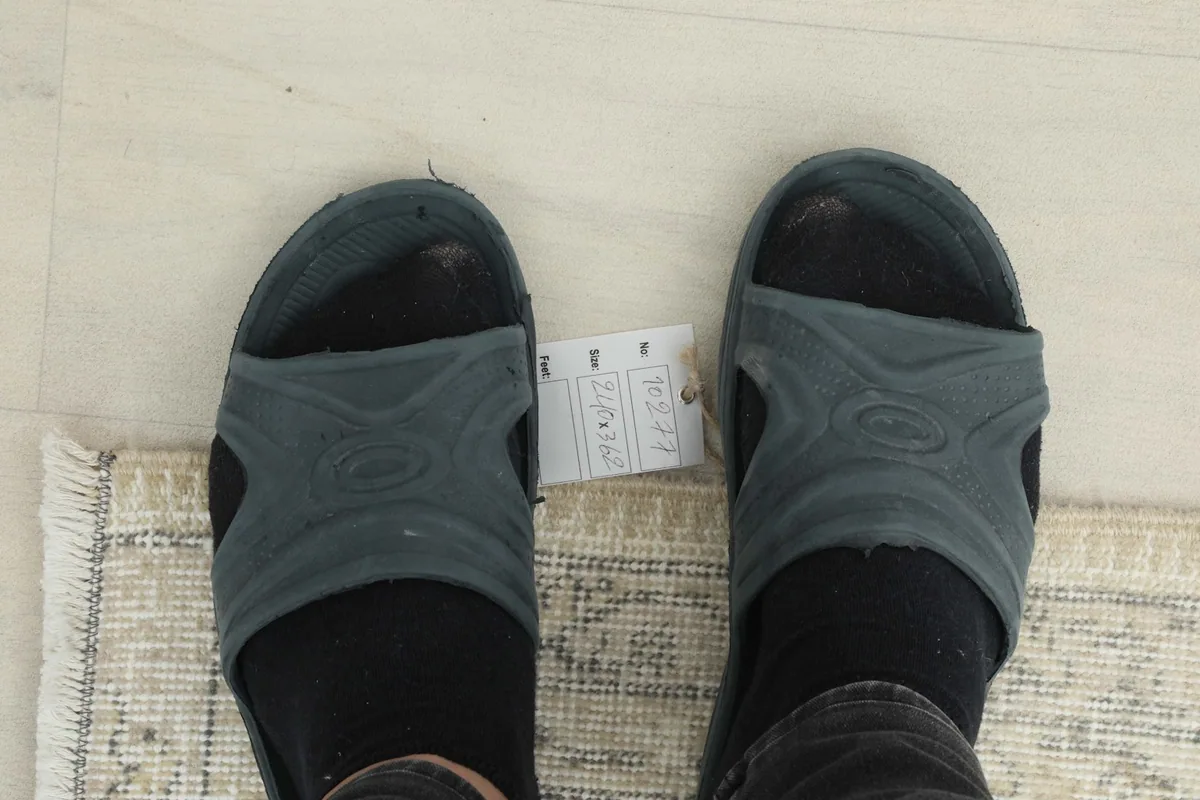 Feet in sandals on the rug, providing a sense of scale and texture.