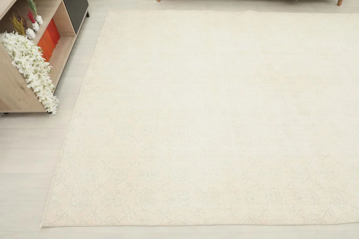 Angled view focusing on the side of the ivory rug, showing its presence next to a furniture piece.