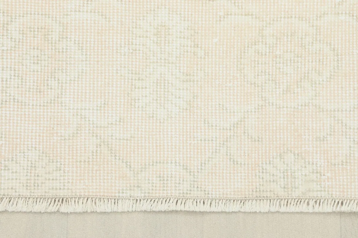 Detail showing the short, natural fringe and edge of the ivory vintage hand-knotted rug.