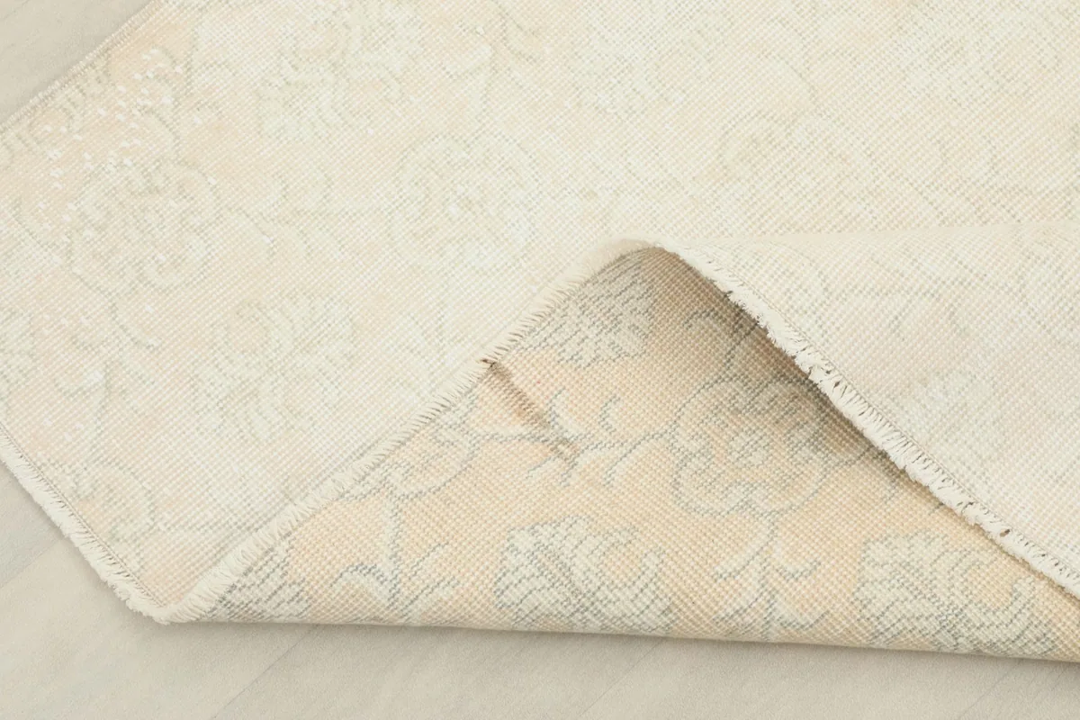 Folded corner of the rug revealing the wool pile on cotton foundation and the reverse side.