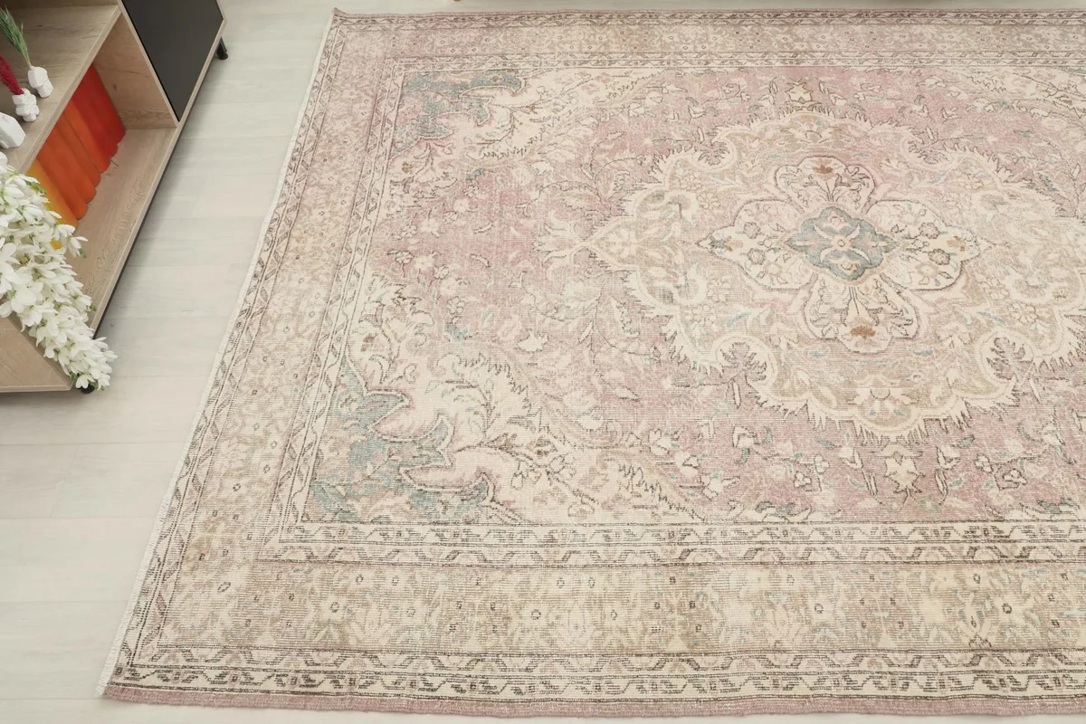 Corner view of the vintage rug, showcasing the beige and green details in the motifs