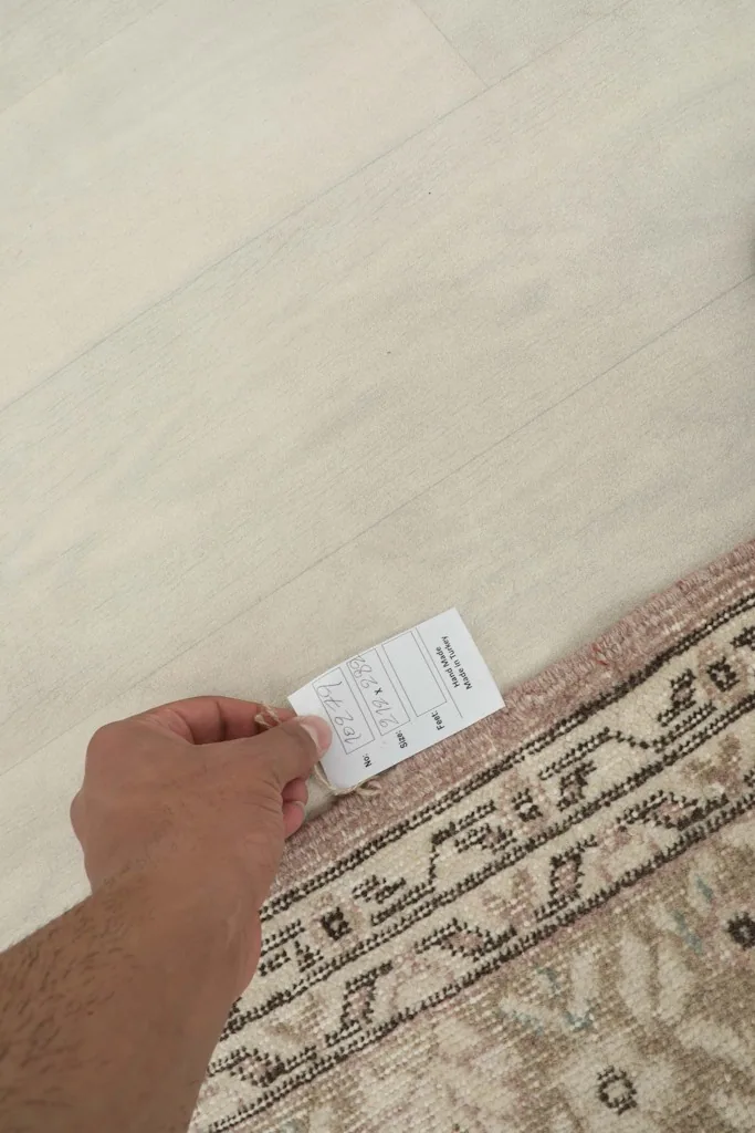 Hand holding a size tag near the border of the vintage Anatolian rug