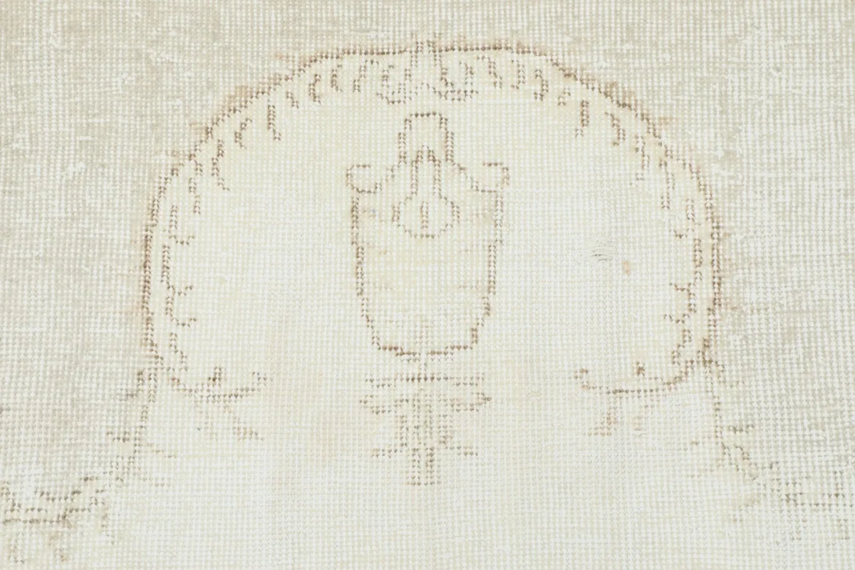 Close-up of a faded motif within the medallion, showcasing the muted tan colors and low pile
