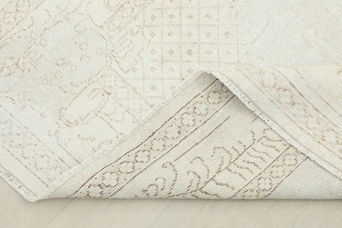 Corner of the rug folded back to show the cotton foundation and hand-knotted construction
