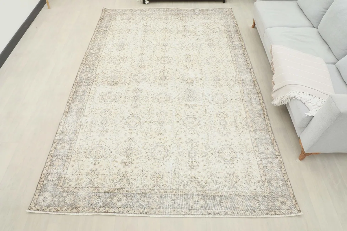 Overview of the ivory and gray vintage rug in a room, providing a sense of its large size and presence.