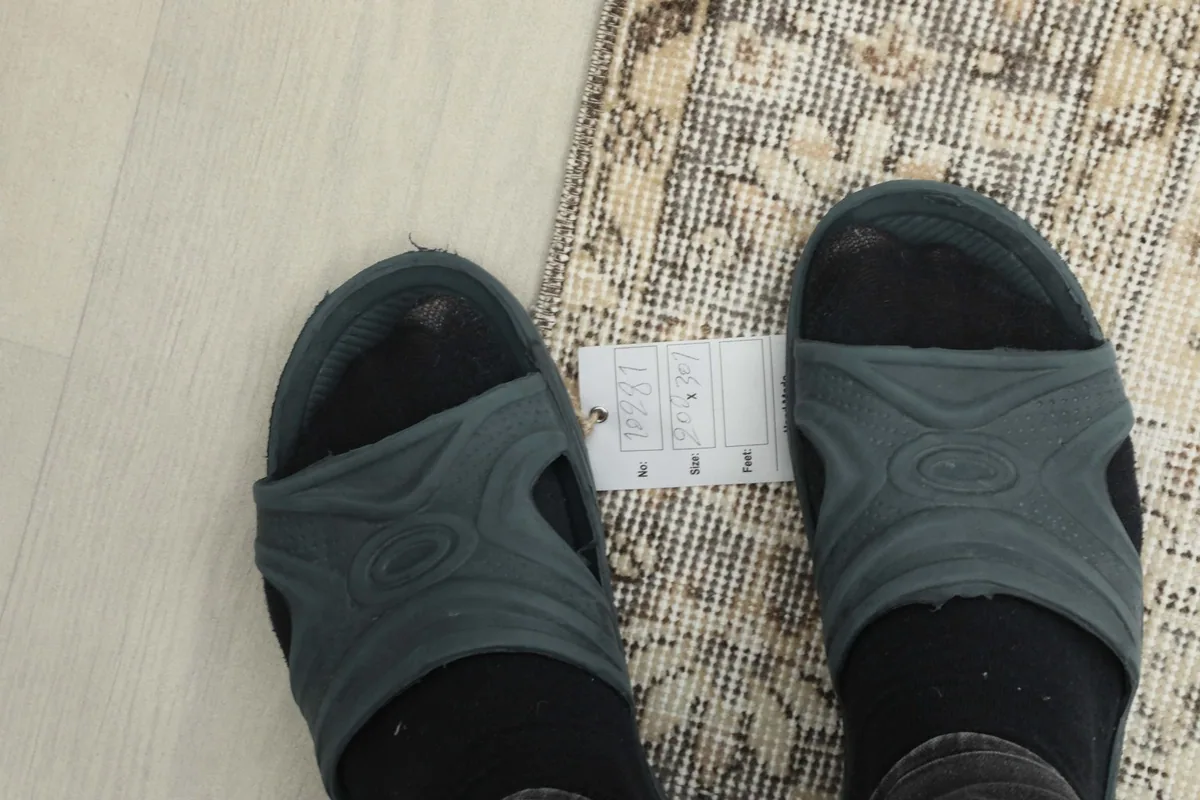 Close-up of the low wool pile and the intricate knotting visible on the rug's surface, with feet for scale.