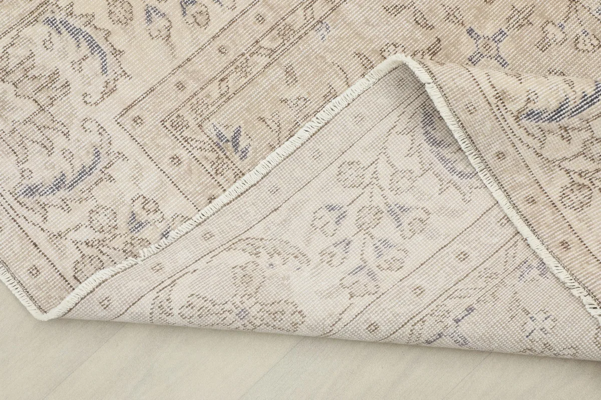 View of the rug's back and folded edge, showing the hand-knotted cotton foundation