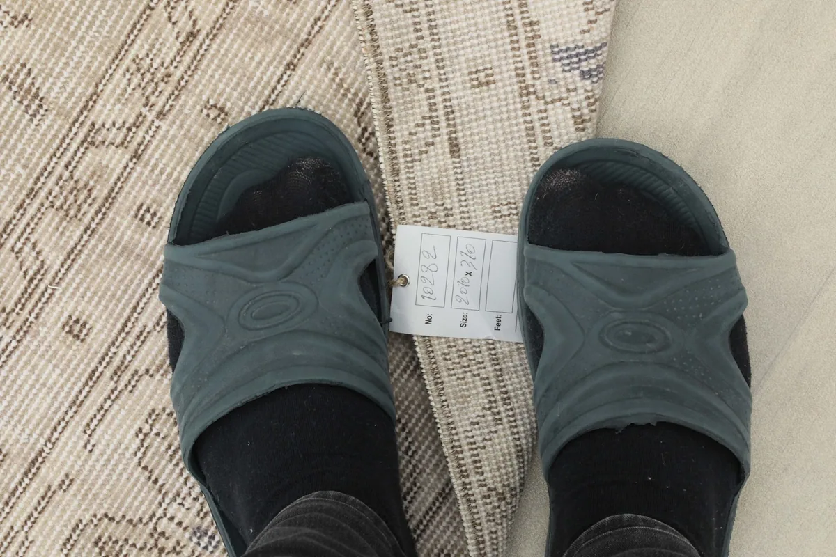 Feet on the rug with a size tag, showing the texture and close-up of the pattern