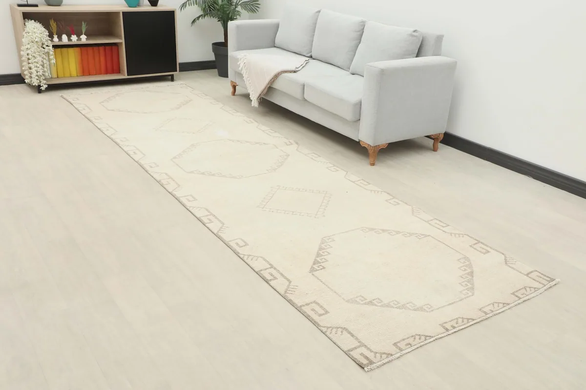 Overhead angle view of the long ivory runner rug in a room, showing its length next to a sofa.