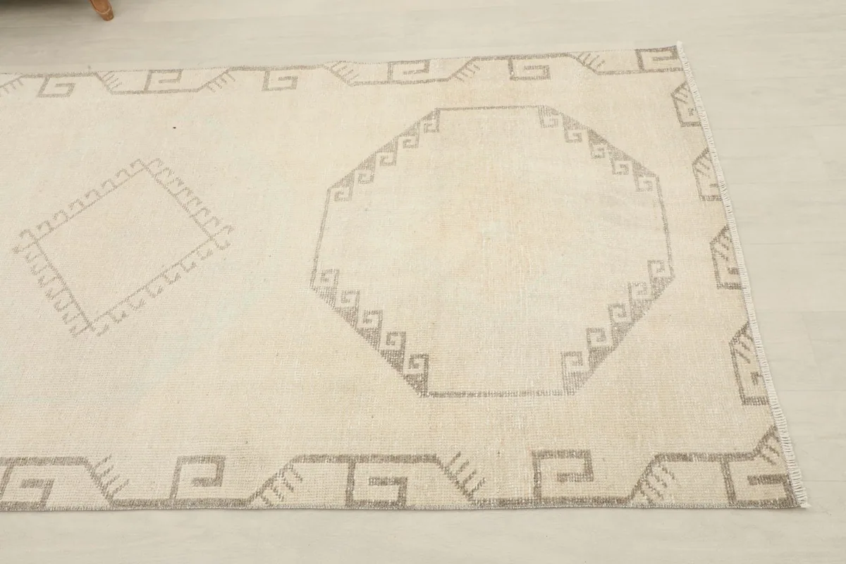 Close-up of the ivory field and gray geometric medallion motif with a border pattern.