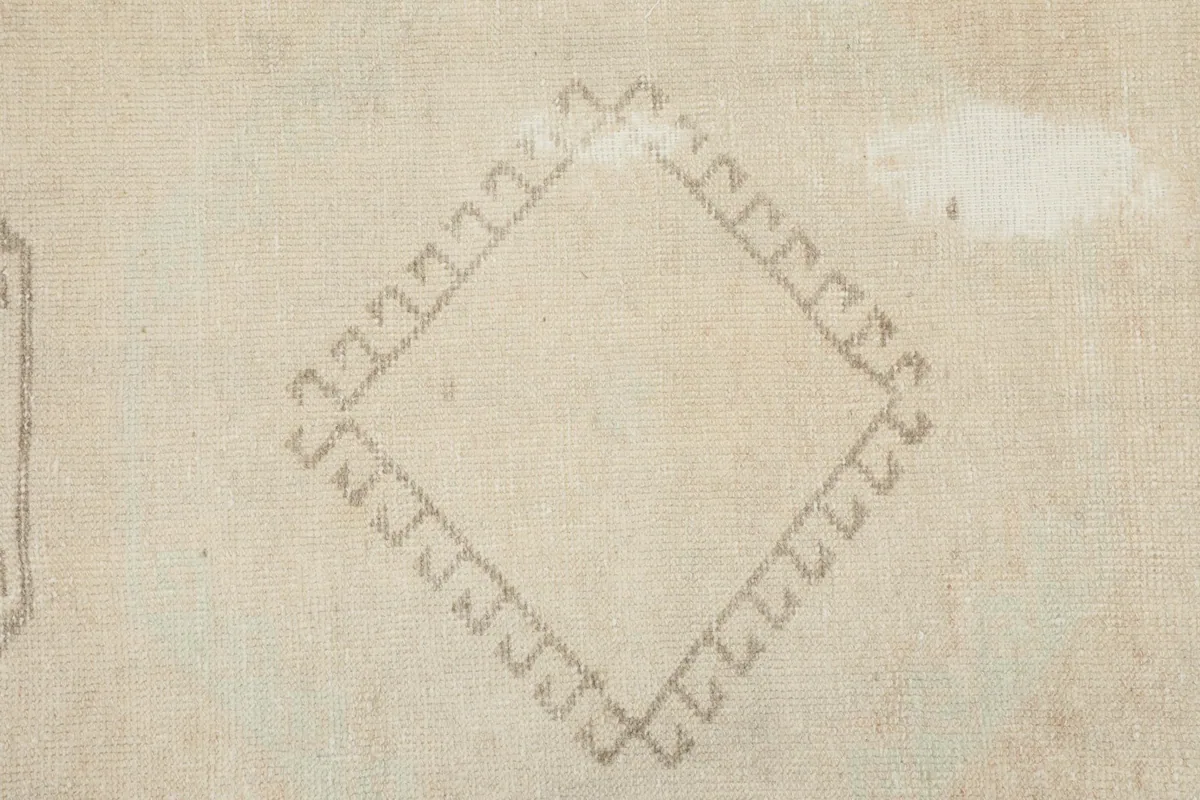 Close-up of a smaller diamond-shaped gray geometric motif on the ivory runner rug.