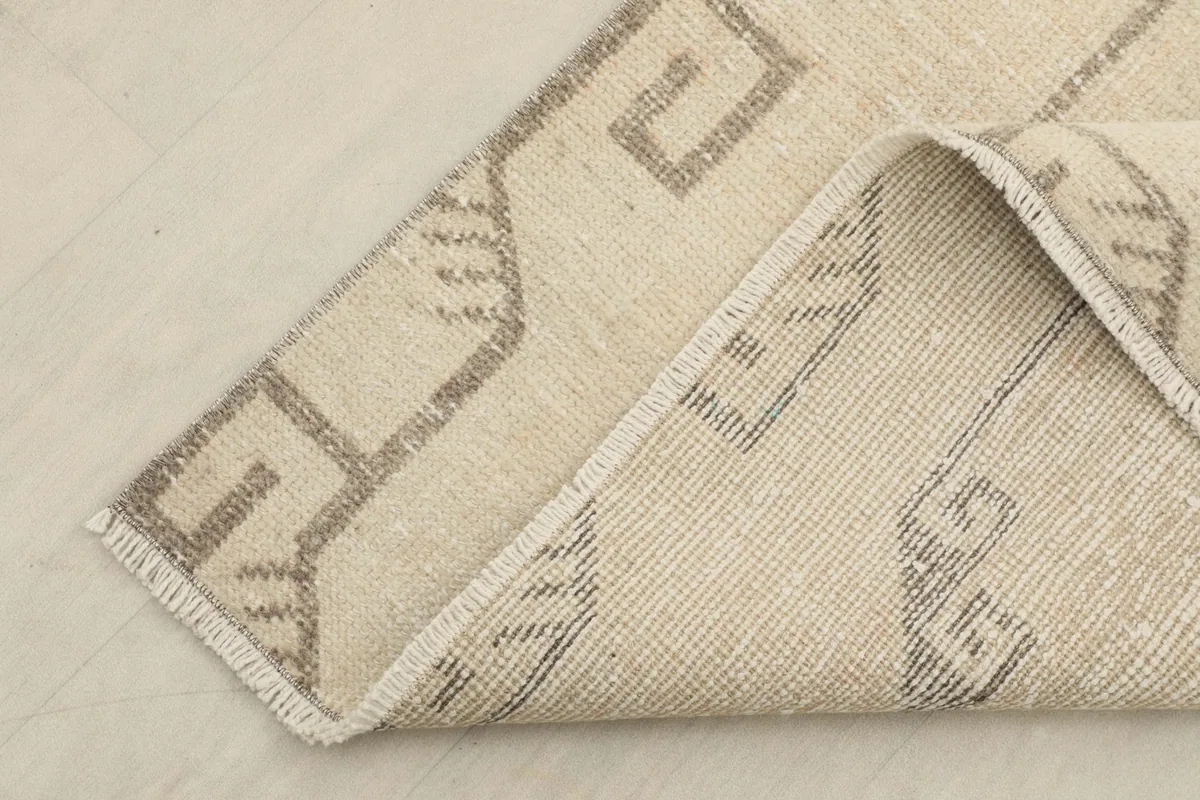 Folded corner of the rug revealing the hand-knotted construction and cotton foundation on the back.
