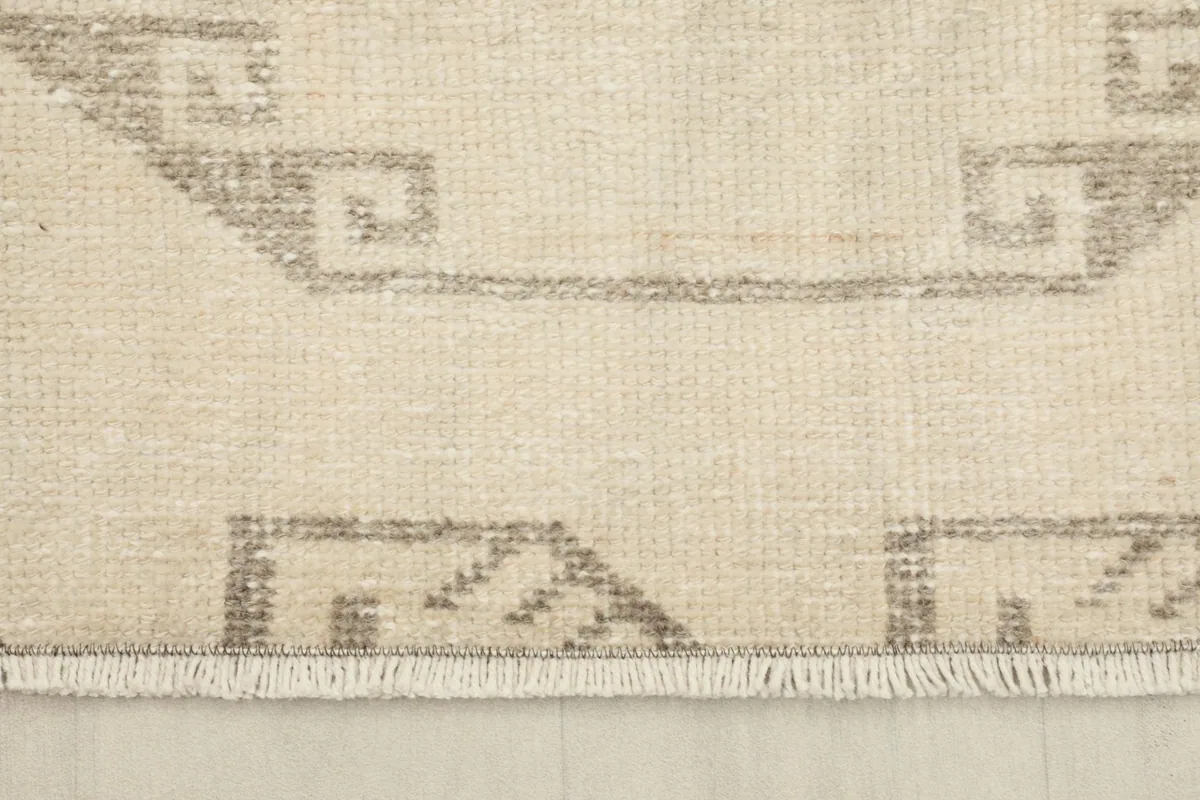 Close-up of the short, hand-finished fringe and the geometric border pattern of the rug.
