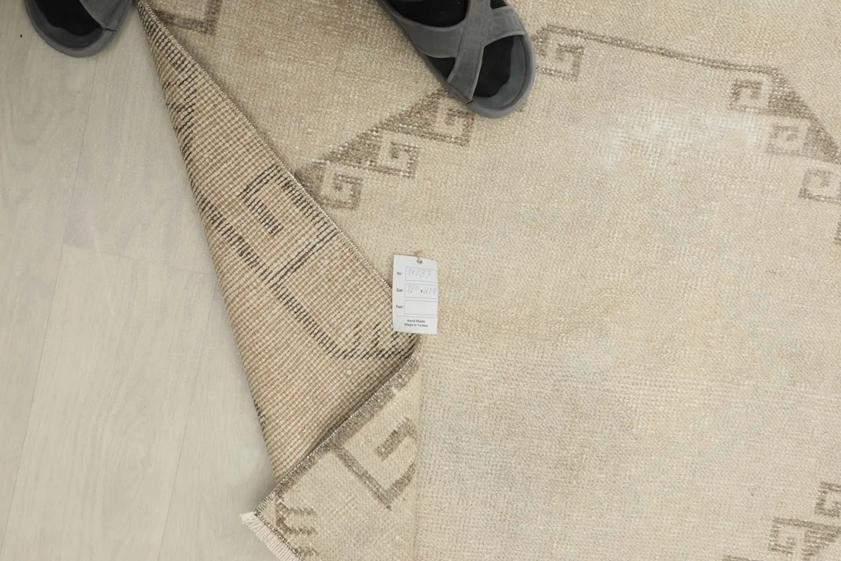 View from above showing a tag on the back of the rug and a pair of sandals next to it for scale.