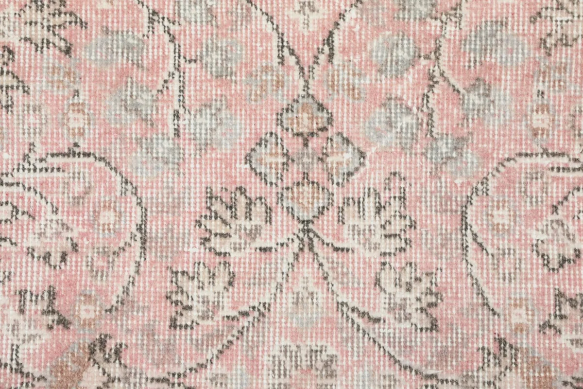 Detailed view of the hand-knotted wool pile, showing the texture and color variations in the rose field.