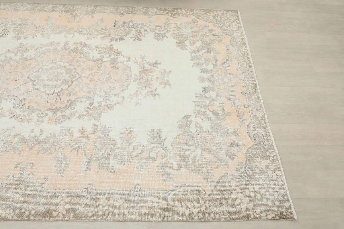 Close-up angled shot of the corner and border design of the vintage rug, showing gray tones.