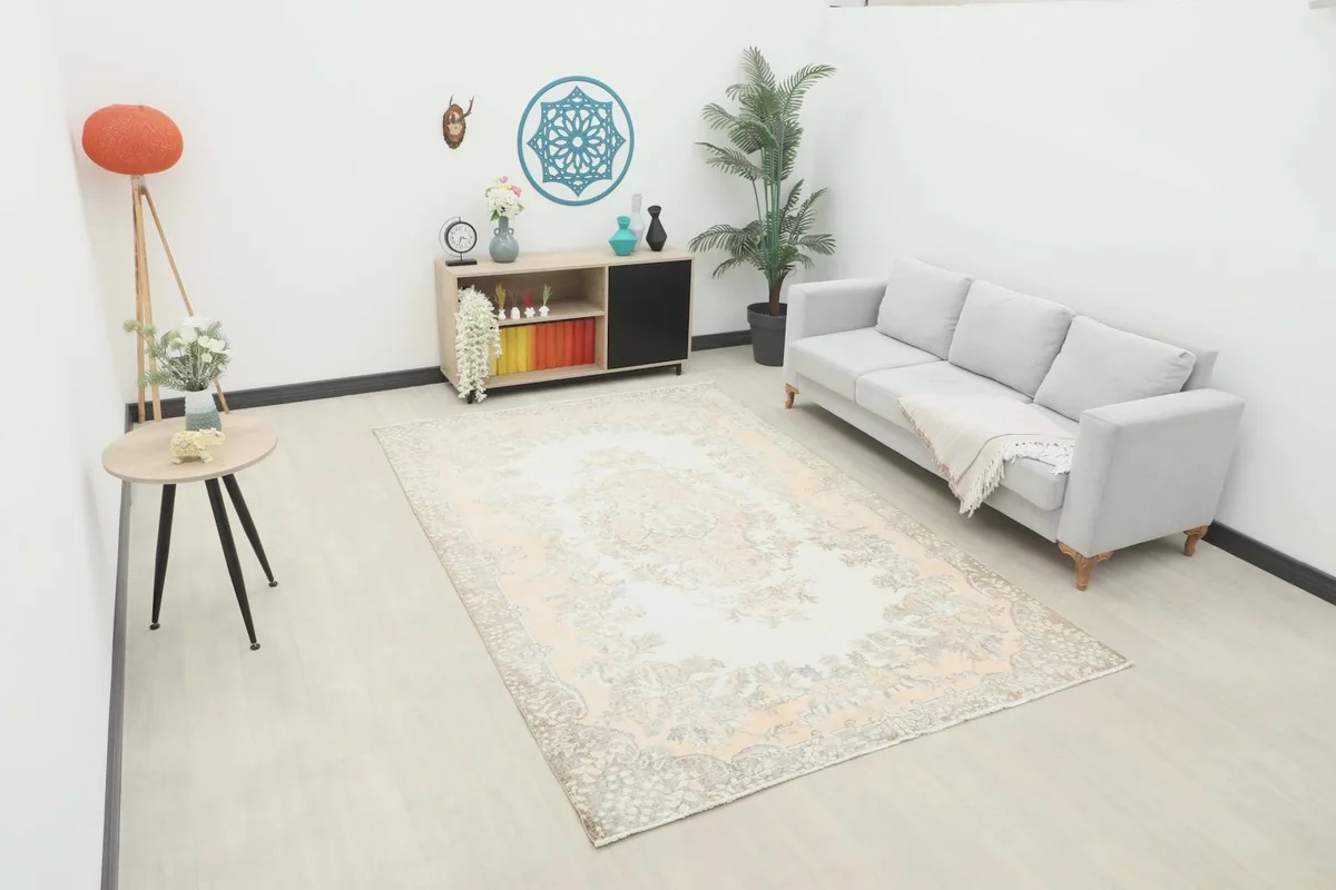 Vintage Anatolian area rug displayed in a living room setting with a sofa and side table.